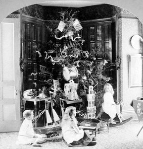 Crianças reunidas aos pés da árvore rodeadas de presentes na manhã de Natal. de Unknown photographer