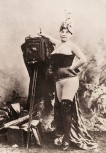 Retrato de uma mulher parcialmente nua, apoiada numa máquina fotográfica antiga. de Unknown photographer