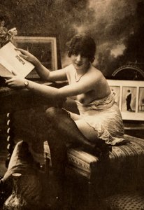 Retrato de uma jovem mulher em trajes íntimos, sentada a uma mesa com um livro. de Unknown photographer