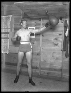 Pugilista inglês William Thomas Wells (Bombardeiro Billy Wells), posando em togs de treinamento com uma bolsa de velocidade, c.1911.