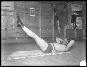 Pugilista inglês William Thomas Wells (Bombardeiro Billy Wells), posando em togs treinamento fazendo elevadores de perna, c.1911