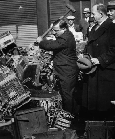Fiorello La Guardia (1882-1947) esmagando slot machines confiscadas de American Photographer