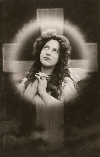 Mulher devota a rezar diante de uma cruz de American School