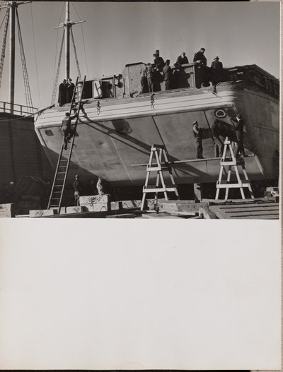 [Um grupo de homens trabalha num barco atracado]. de Arnold Eagle