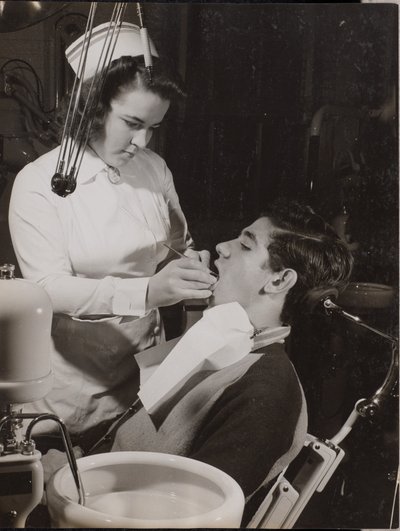 [O higienista dentário inspecciona a boca de um paciente]. de Arnold Eagle