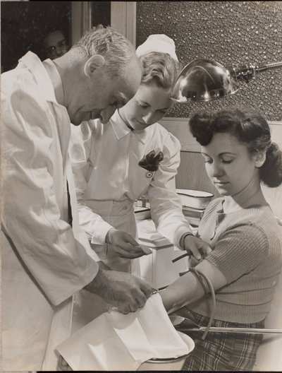 [Médico e enfermeira introduzem uma agulha no braço de uma mulher]. de Arnold Eagle