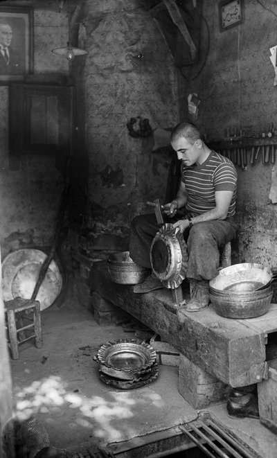 Um metalúrgico italiano martelando numa folha de metal para fazer um vaso ou pote em relevo, Itália de Bernard F. Rogers