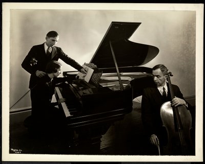 Mulher cega, Miss Harding, ao piano instruindo dois cegos no violino e violoncelo, 1936 (impressão de gelatina de prata) de Byron Company