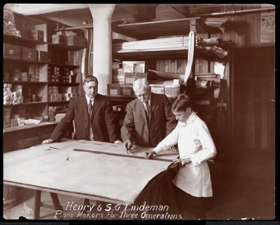 Retrato de Henry e SG Lindeman com seu filho ou neto de pé sobre desenhos de loja para um piano, 1910 (impressão de gelatina de prata) de Byron Company