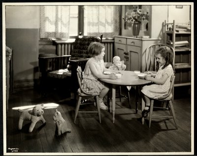Duas meninas cegas com deficiência visual comendo em uma pequena mesa com boneca na Associação Nova Iorque para os Cegos, 111 East 59th Street, Nova York, 1933 (impressão em gelatina de prata) de Byron Company