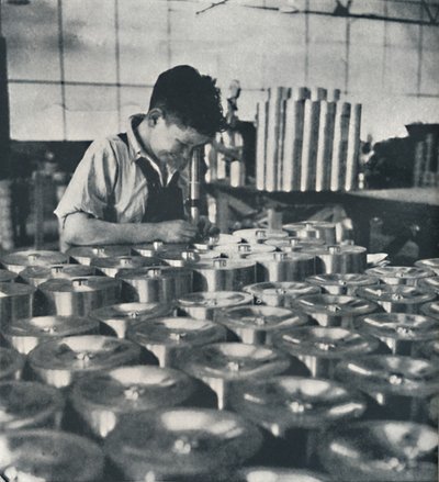 Aprendiz com microscópio testando a dureza dos pistões, 1941 de Cecil Beaton