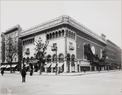 Um teatro enorme com uma fachada elaborada, completo com arcos e varandas mouriscas. Uma grande placa no topo do edifício diz "B.S. Moss Regent Theatre Vaudeville & Feature Films". Uma placa publicitária de Olga Petrova em "O Coração de uma Mulher Pintada" de Company Byron