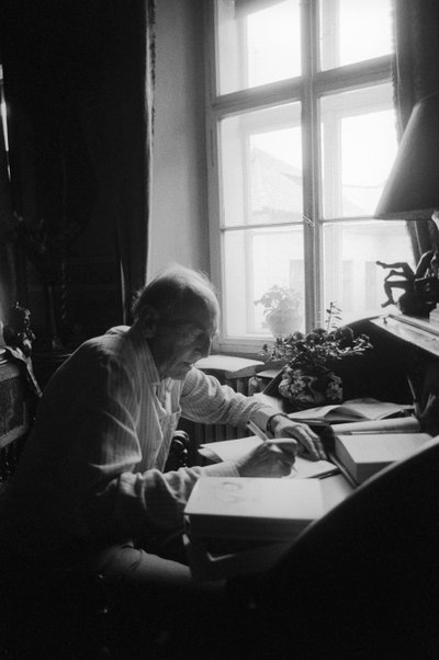 Jiri Mucha sentado em sua mesa em sua casa em Hradcany, Praga de Czech Photographer