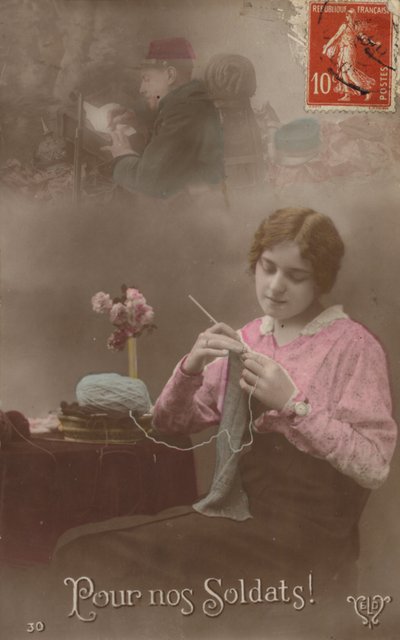 Uma jovem tricota enquanto pensa em seu soldado que está escrevendo uma carta para casa (foto colorida) de French Photographer
