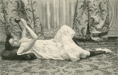 Menina, deitada no chão, segurando uma bola acima da cabeça (foto a p/b) de French Photographer