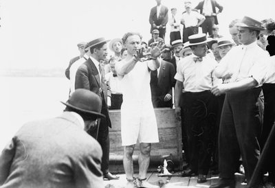 Harry Houdini sendo algemado antes de ser pregado em uma caixa e abaixado na Baía de Nova York, 1912 de George Grantham Bain