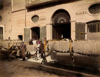 Fileiras de secadores de maccheroni em frente a uma fábrica em Torre Annunziata. A cena é animada pelos empregados da fábrica de massas: alguns estão posando, em primeiro plano, perto das secadoras, outros estão no limiar das entradas da fábrica. de Giorgio Sommer