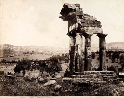 Vista das quatro colunas restantes que suportam uma entablatura do Templo de Castor e Pollux no Valle dei Templi, Agrigento. Um panorama da cidade é visível em segundo plano. de Giorgio Sommer