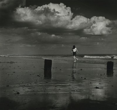 Criança a brincar com as ondas na praia. de Godfrey Macdominic