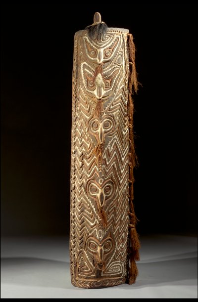Escudo Sepik retangular curvo, a frente com faixa central de cinco máscaras, cada uma com fibra no septo perfurado, dentro do painel de ziguezagues esculpidos (madeira, penas e ráfia) de Guinean New