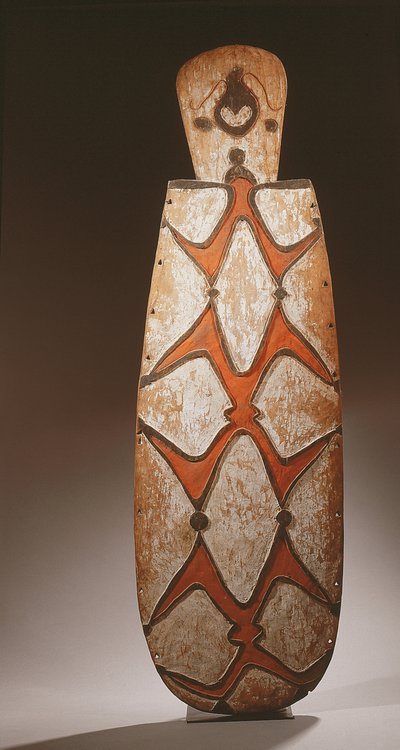 Escudo oval Asmat, entalhado em relevo com figuras estilizadas, máscara no topo (madeira) de Guinean New
