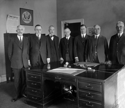 Conselho da Reserva Federal, da esquerda para a direita: Secretário Mellon; W.P.G. Harding; Vice-Governador Edmund Platt; Charles S. Hamlin; Adolph Miller; Controlador D.R. Crissinger, e J.R. Mitchell. Fotografia de Harris & Ewing, c. 1905 / 1945. de Harris & Ewing