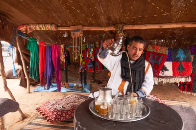 Um habitante local serve chá de menta no Erg Chebbi, no deserto perto de Merzouga, Marrocos, 2019 (foto) de Ira Block