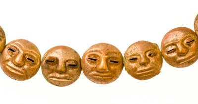 Um colar encontrado à volta do pescoço da múmia com pequenos rostos de ouro. de Ira Block