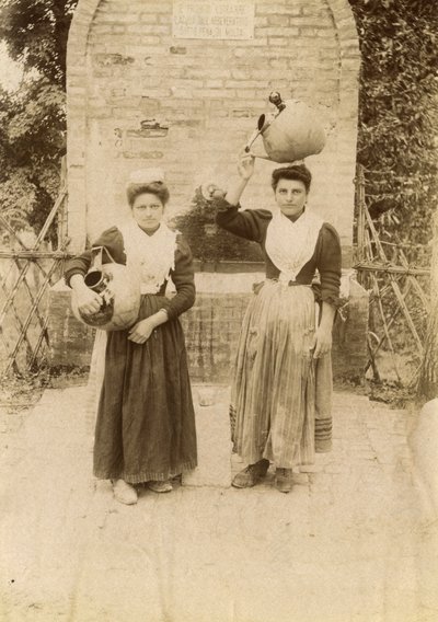 Duas jovens mulheres vestindo roupas tradicionais e carregando jarros de terracota perto de um poço, Marche, Itália, cerca de 1910 de Italian Photographer