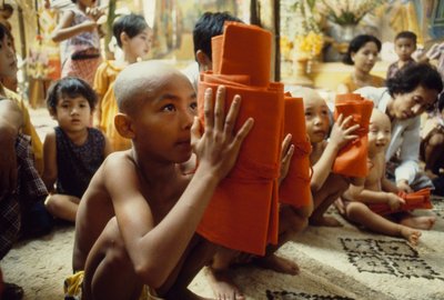 Um jovem rapaz com a cabeça rapada recebe a sua roupa de monge. Mandalay, Birmânia. de James L Stanfield
