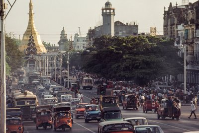 Carros antigos entopem o centro da cidade de Rangoon, capital da Birmânia. Estrada do Pagode Sule, R... de James L Stanfield