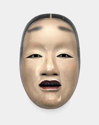 Uma máscara de madeira com fundo de gofun, pintada com sumi para os cabelos, olhos e dentes e vermelha para os lábios de Japanese School