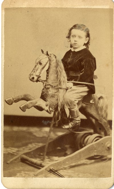 Rapazinho com chicote no cavalo de balanço de John McCaffrey