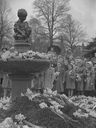Crianças a colocar ramos de narcisos na fonte com uma estátua no topo de Joseph Hardman