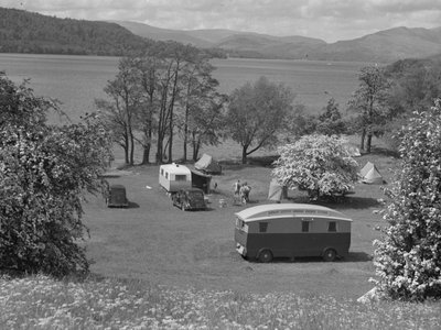 Tendas e caravanas instaladas num campo em Wastwater, com o lago e as montanhas ao fundo de Joseph Hardman