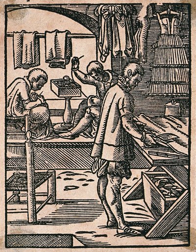 Um alfaiate corta tecido com tesouras enquanto os seus colegas cosem a uma bancada. Xilogravura de J. Amman. de Jost Amman