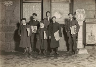 8:30 P.M. Grupo de jornaleiros a vender no depósito, Hartford, Connecticut. O rapaz mais pequeno tem 11 anos de idade, março de 1909 (foto) de Lewis Wickes Hine