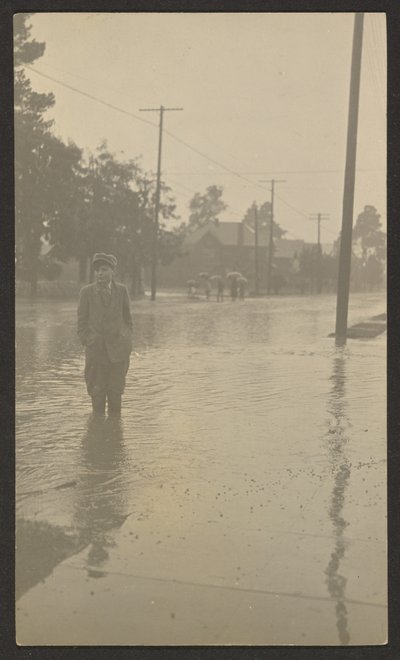 [Rapaz em pé numa rua inundada]. de Louis Fleckenstein