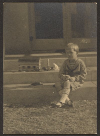 [Rapaz com brinquedos nos degraus]. de Louis Fleckenstein