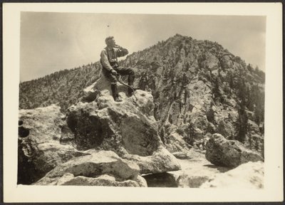 [Homem sentado em cima de rochas]. de Louis Fleckenstein