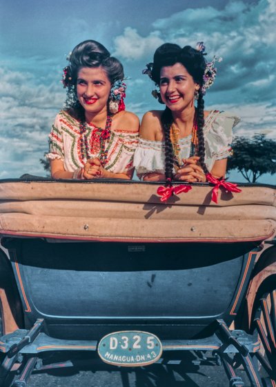 Jovens mulheres nicaraguenses posam em trajes festivos e chapéus na parte de trás de uma carruagem ak... de Luis Marden