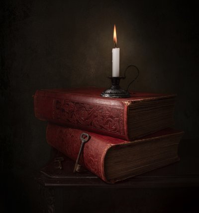 Livros à luz de velas e uma chave de Margareth Perfoncio