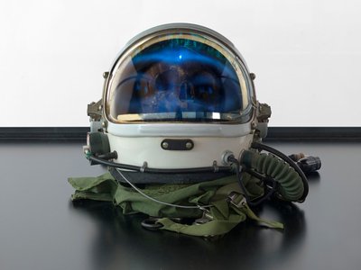 Alpha Omega, 2016 (Vidro, ecrã LCD, leitor multimédia, réplica de crânio, capacete espacial, madeira) de Mat Collishaw