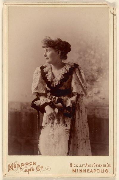 [Mulher não identificada de perfil, apoiada numa cadeira, segurando um leque de penas] de Murdock and Company