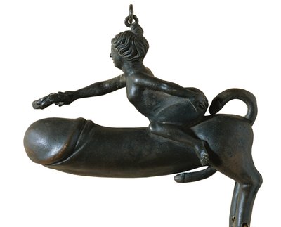 Falo de Sasamon. 1º c. Animal com peito, pernas e glande em forma de cauda, montado por uma mulher com coroa de louros. Amuleto contra o mau-olhado. Arte romana. Início do Império. Escultura sobre bronze. ESPANHA. CATALÓNIA. BARCELONA. Barcelona. Museu de  de Roman Roman