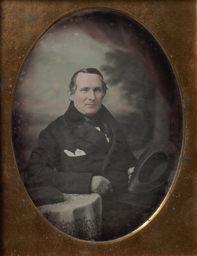Homem vestindo casaco e luvas, segurando o chapéu, sentado na frente do pano de fundo pintado ao ar livre, década de 1840. de Samuel Broadbent Jr..