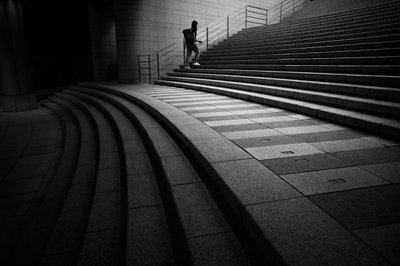Homem a subir uns degraus urbanos de Satoshi Hata