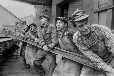Trabalhadores da mina juntam-se para mover um pesado carril de aço na mina de cobre El Teniente... de Ted Spiegel