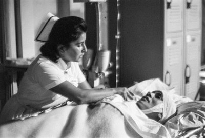 Enfermeira assiste um doente em maca após uma cirurgia no navio-hospital SS Hope de Ted Spiegel