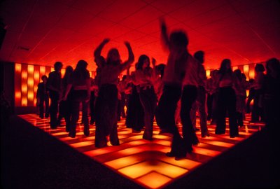 Jovens bailarinos numa discoteca a dançar numa pista iluminada de Ted Spiegel